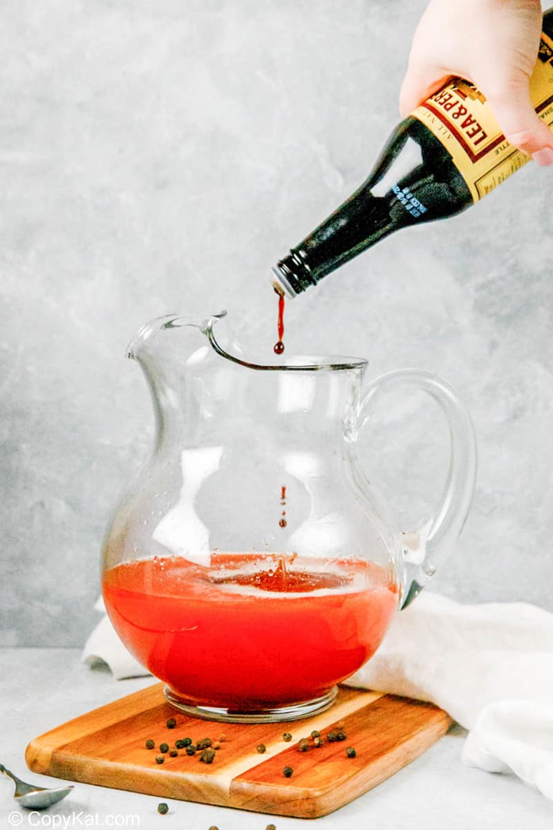 pouring Worcestershire sauce into a pitcher of homemade bloody mary mix