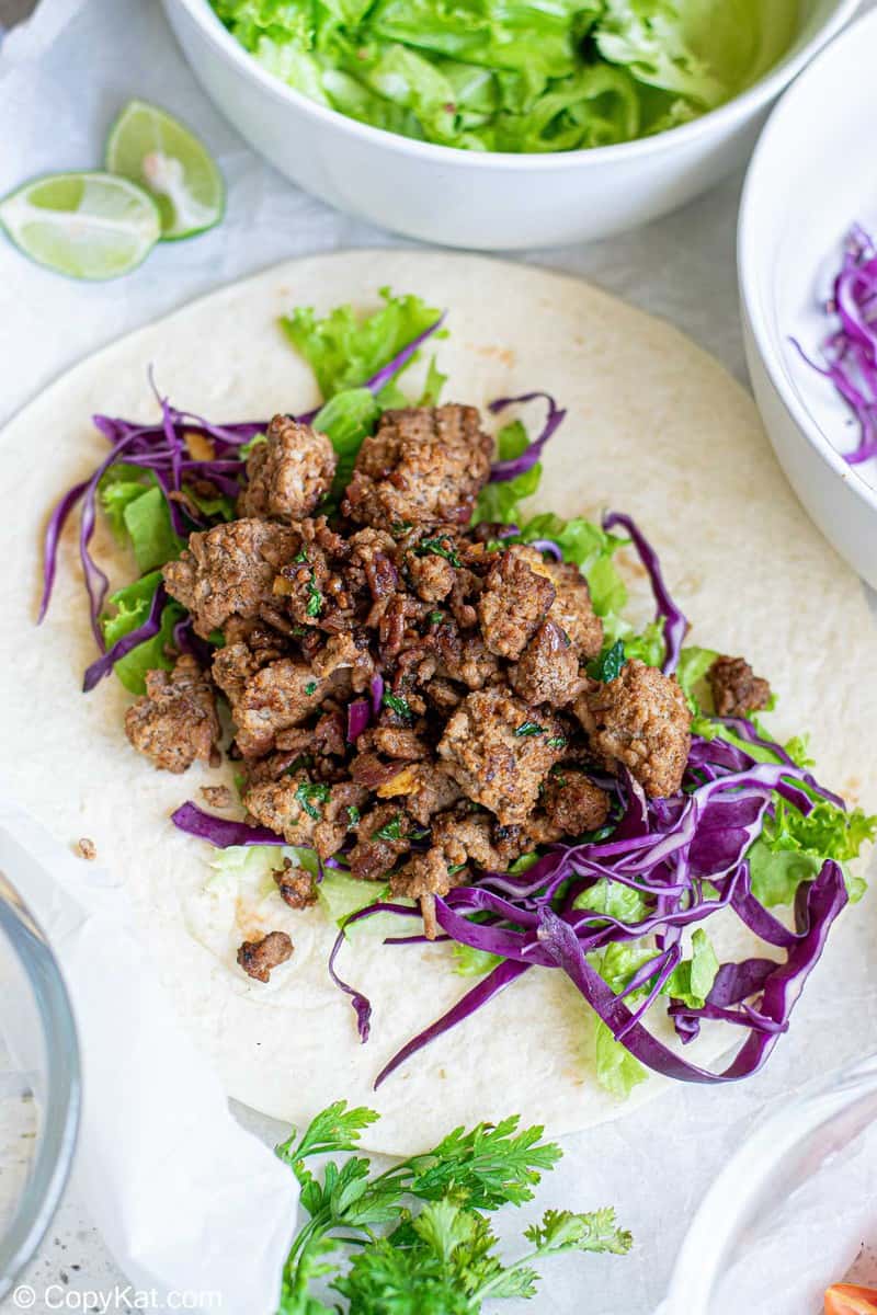 lettuce, cabbage, and cooked ground beef on a flour tortilla