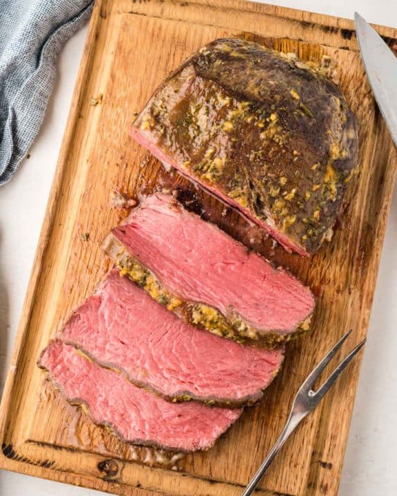 overhead view of cooked and sliced NY strip roast on a cutting board