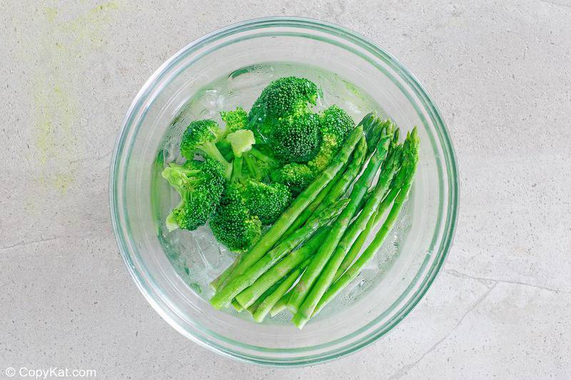 blanched asparagus and broccoli in an ice bath