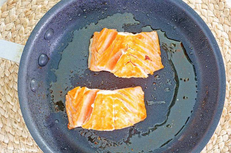 frying two pieces of salmon in a skillet