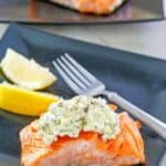 pan fried salmon with pesto cream cheese sauce and a fork on a plate