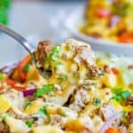 homemade Taco Nacho Fries BellGrande on a fork over a plate of them