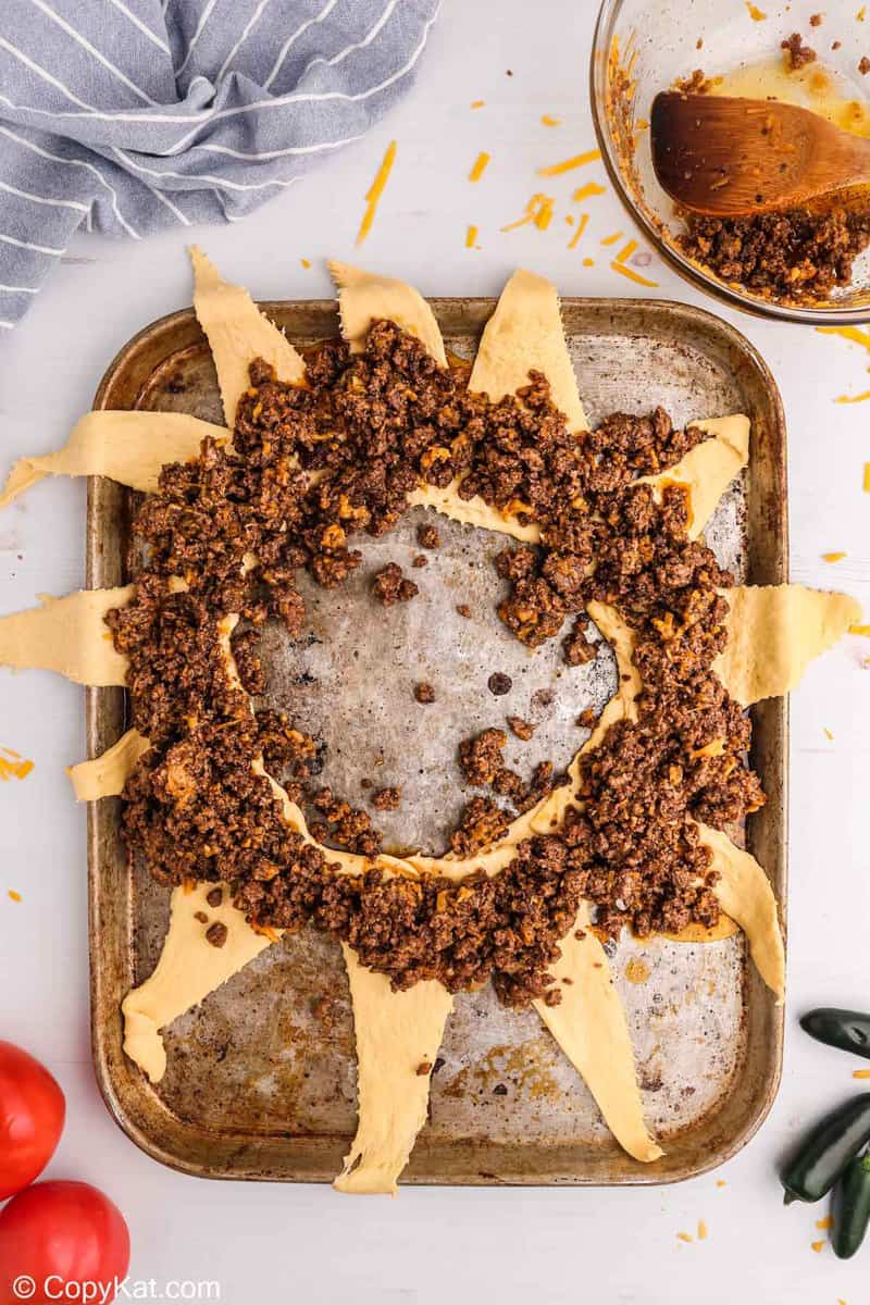 seasoned ground beef and cheese on top of crescent roll triangles