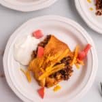 piece of a taco ring and sour cream on a plate