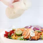 pouring creamy salsa verde salad dressing on chicken fajita salad