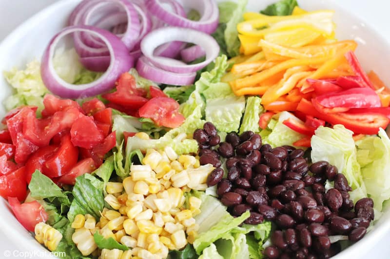 romaine, tomatoes, onions, peppers, corn, and black beans in a bowl