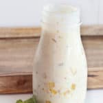 creamy salsa verde salad dressing in a jar next to a wood tray