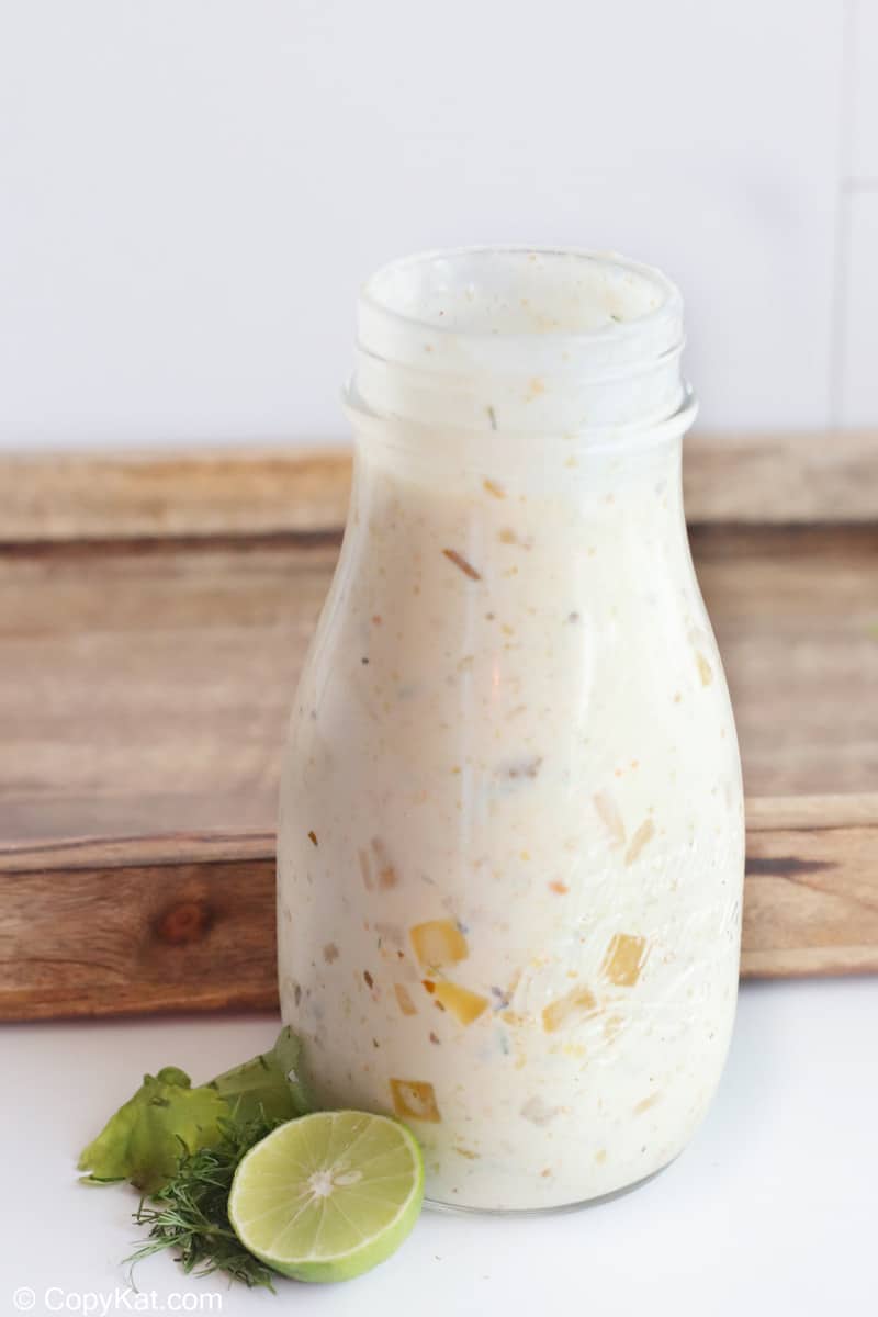 creamy salsa verde salad dressing in a jar next to a wood tray