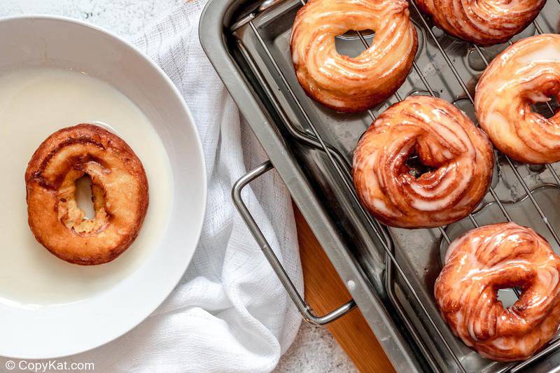 dipping a French cruller into glaze