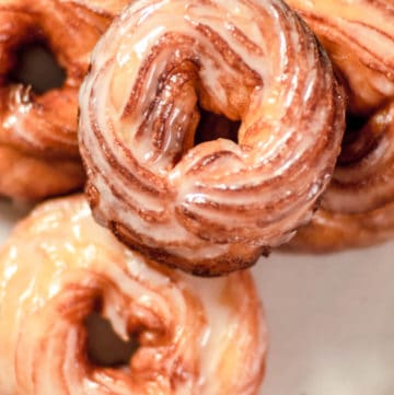 overhead view of four French cruller donuts on a plate