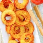 overhead view of fried apples, an apple, and wood tongs