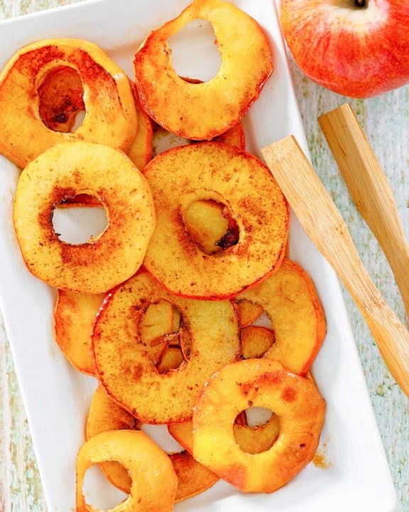 overhead view of fried apples, an apple, and wood tongs