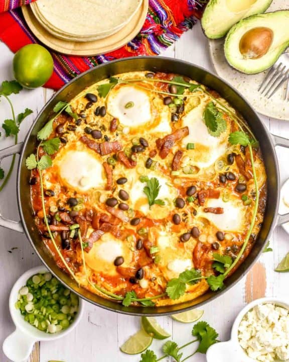 huevos rancheros in a pan, corn tortillas, avocado, and cojita cheese