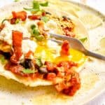 fork breaking the egg yolk on huevos rancheros