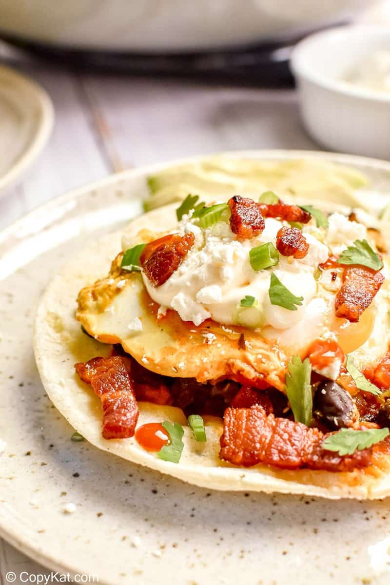 huevos rancheros topped with crema fresca and bacon