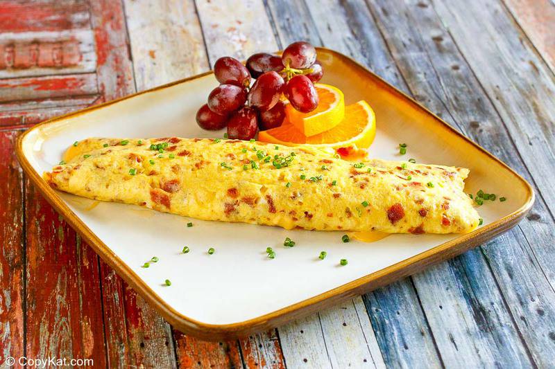 homemade IHOP Bacon Temptation Omelette, grapes, and orange slices on a plate