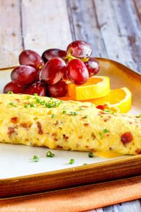 bacon and cheese omelette and fruit on a plate