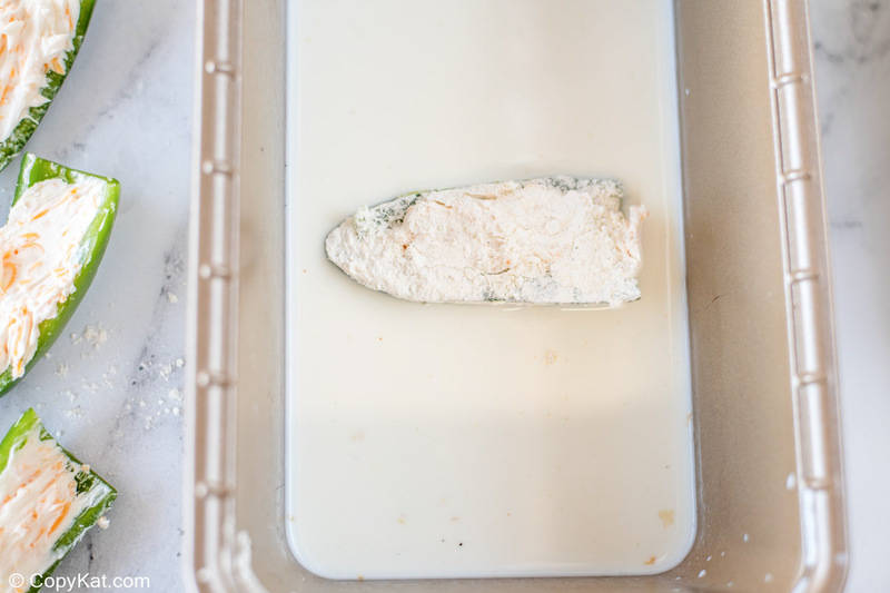 a flour coated cheese stuffed jalapeno pepper in milk