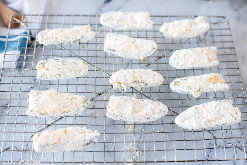 flour coated cheese filled jalapeno peppers on a wire rack