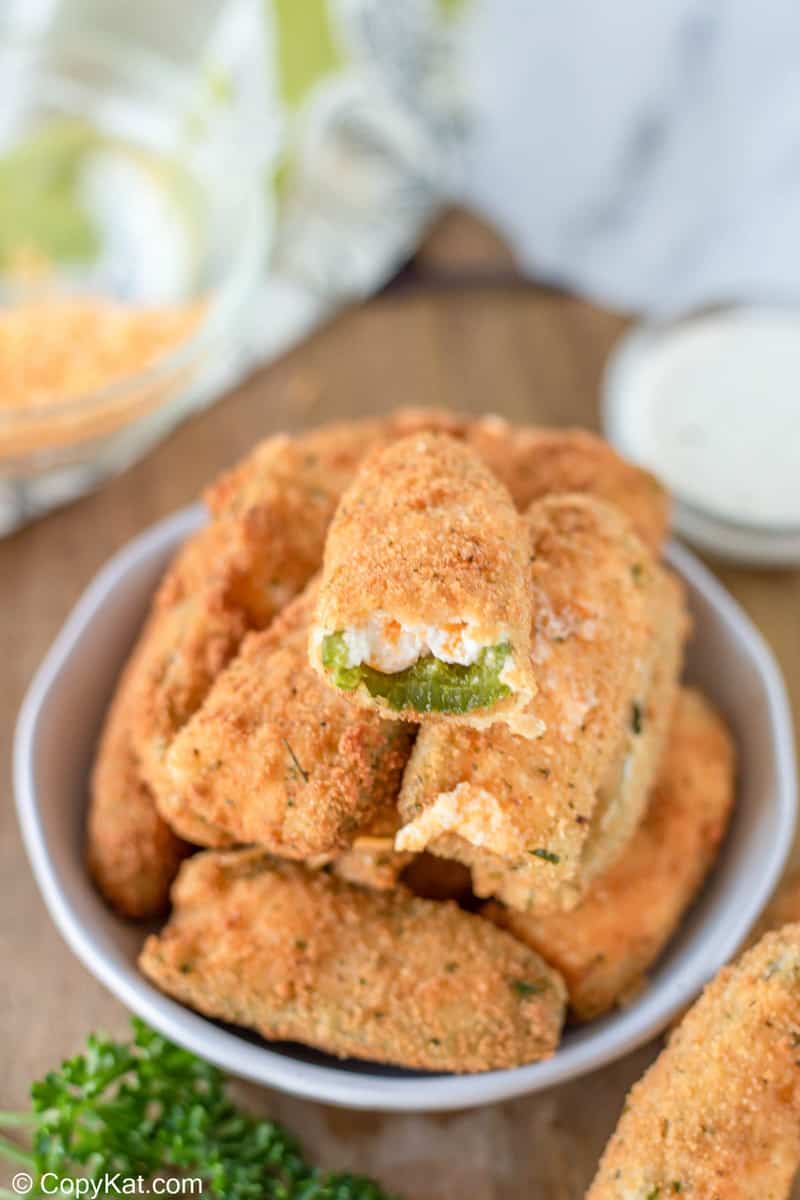 jalapeno popper with a bite taken out of it on top of a pile of the poppers