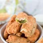 a bowl of jalapeno poppers with a bite taken out of the one on top