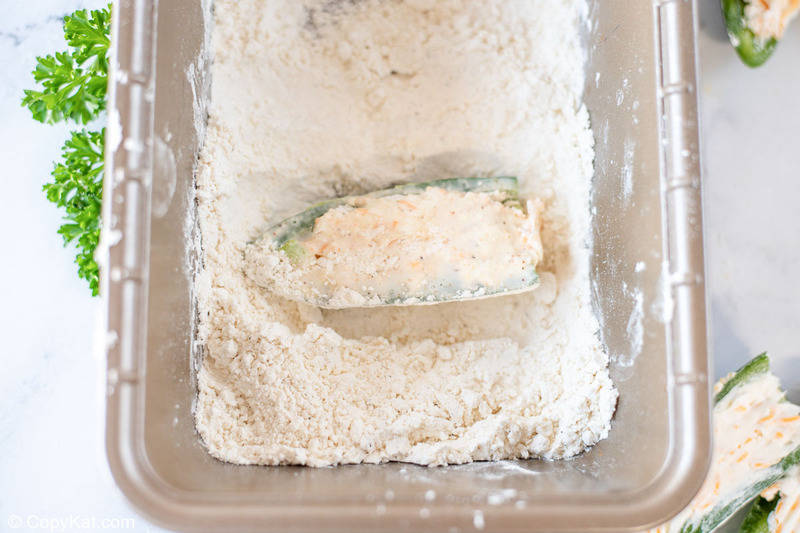 coating a cheese stuffed jalapeno pepper in flour
