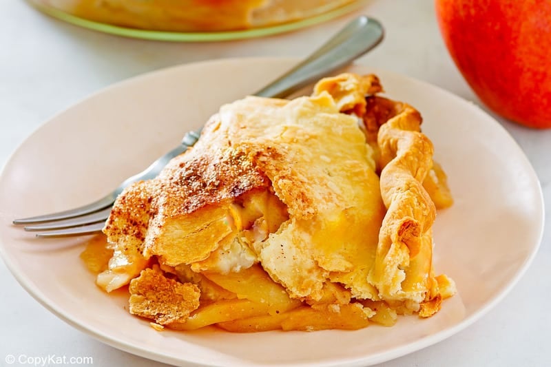 a slice of old fashioned apple pie and a fork on a plate