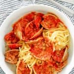 overhead view of red clam sauce, clams, and pasta in a bowl