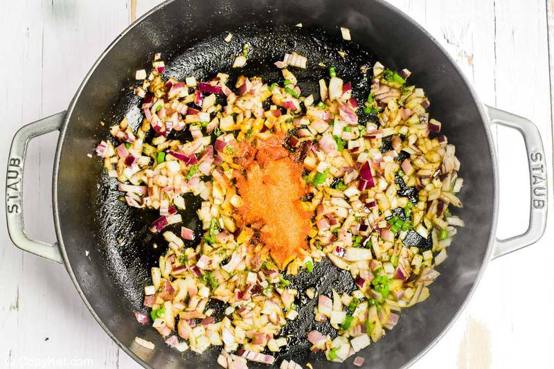Sazon seasoning added to cooked onions in a pan