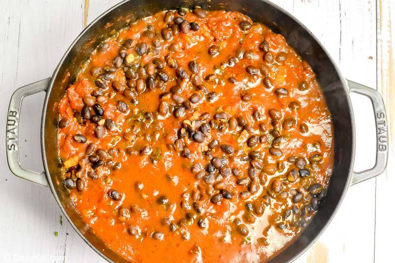 tomato sauce with black beans and bacon for huevos rancheros in a pan
