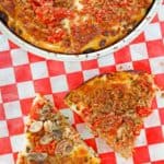 two slices of deep dish pizza with sausage next to the pizza