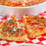 homemade deep dish pizza in pans and slices on parchment paper