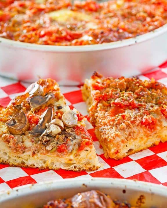 homemade deep dish pizza in pans and slices on parchment paper