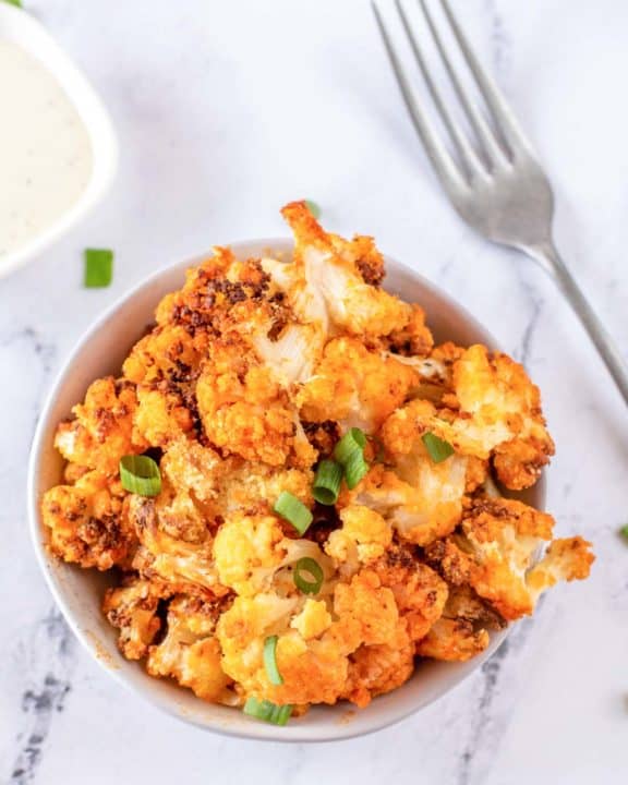 a bowl of air fryer buffalo cauliflower, fork, and dressing
