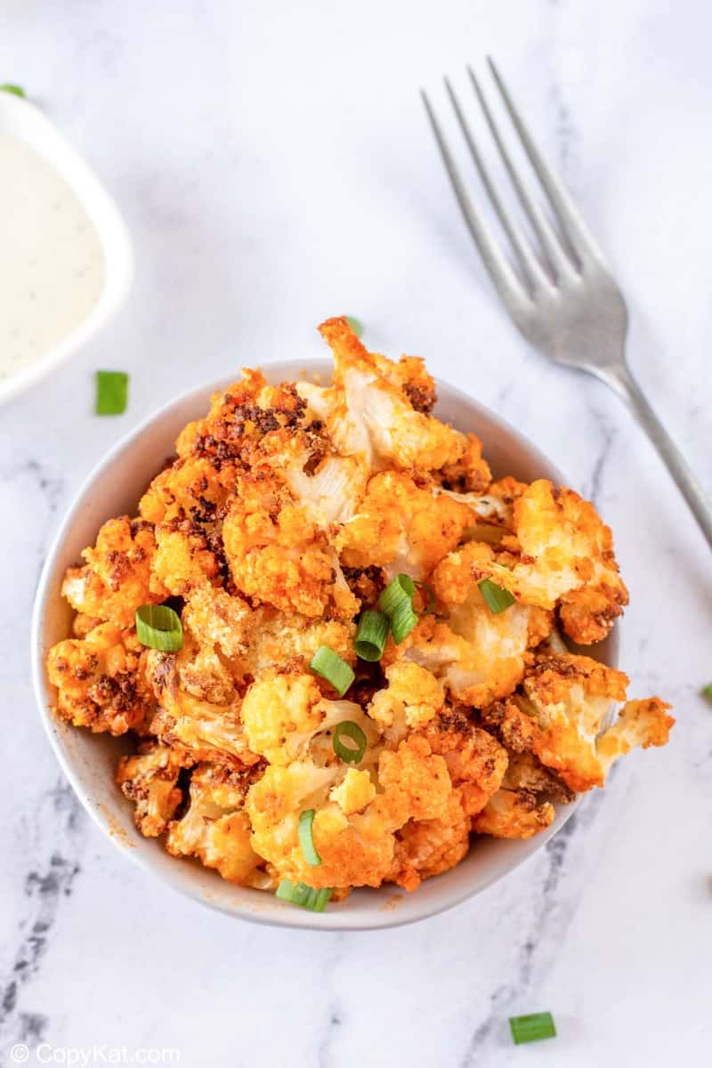 a bowl of air fryer buffalo cauliflower, fork, and dressing