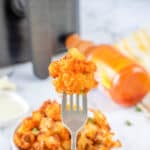 air fryer buffalo cauliflower bite on a fork over a bowl of the cauliflower