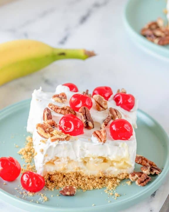 banana split cake slice on a plate next to a banana