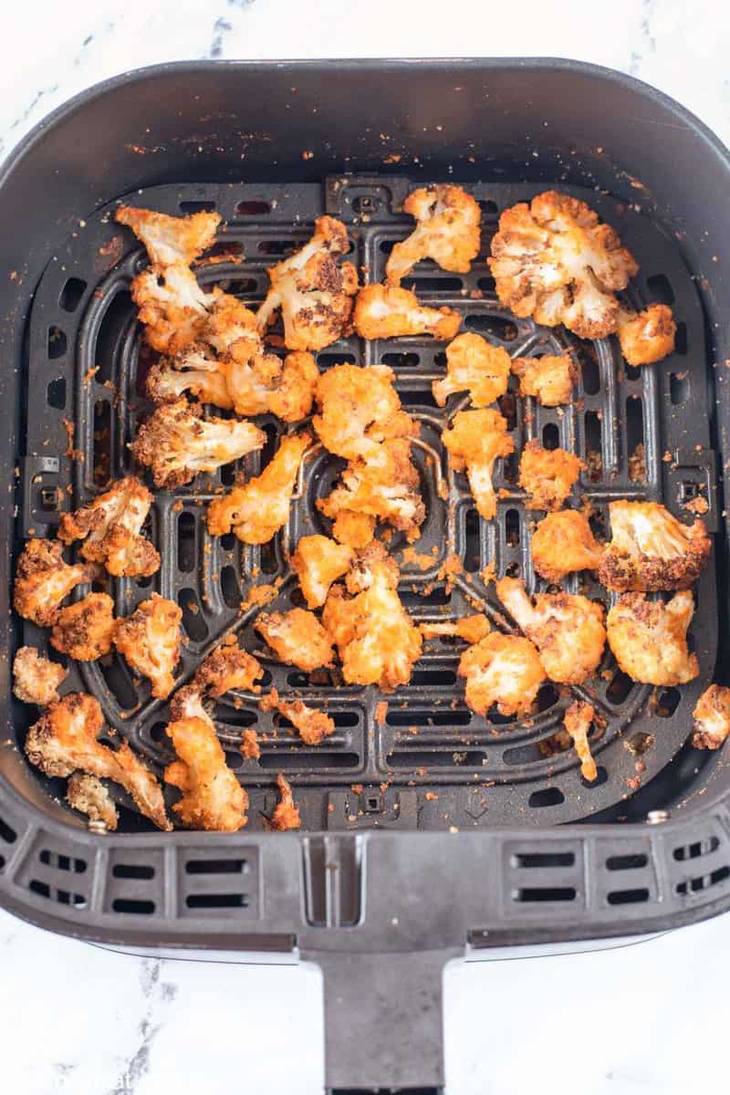 cooked buffalo cauliflower in an air fryer basket