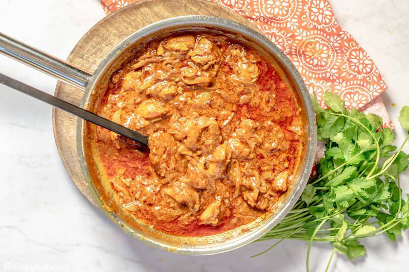 Indian butter chicken in a pan and fresh cilantro