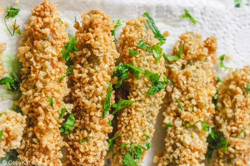 deep fried pickles garnished with chopped parsley on paper towels