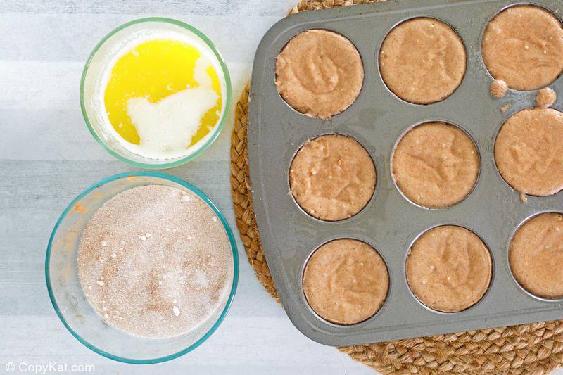 donut muffin batter in a muffin pan, melted butter, and cinnamon sugar mixture