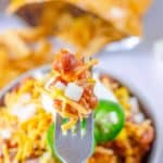 Frito pie on a fork over a bowl of it