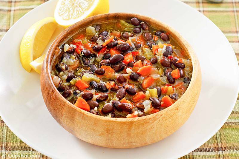 a bowl of homemade Panera black bean soup and lemon slices on a plate