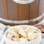 homemade peanut butter ice cream with peanut butter cups in a bowl in front of an ice cream maker