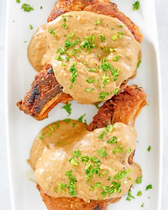 overhead view of two pork chops and gravy on a platter