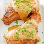 two pork chops topped with gravy on a platter