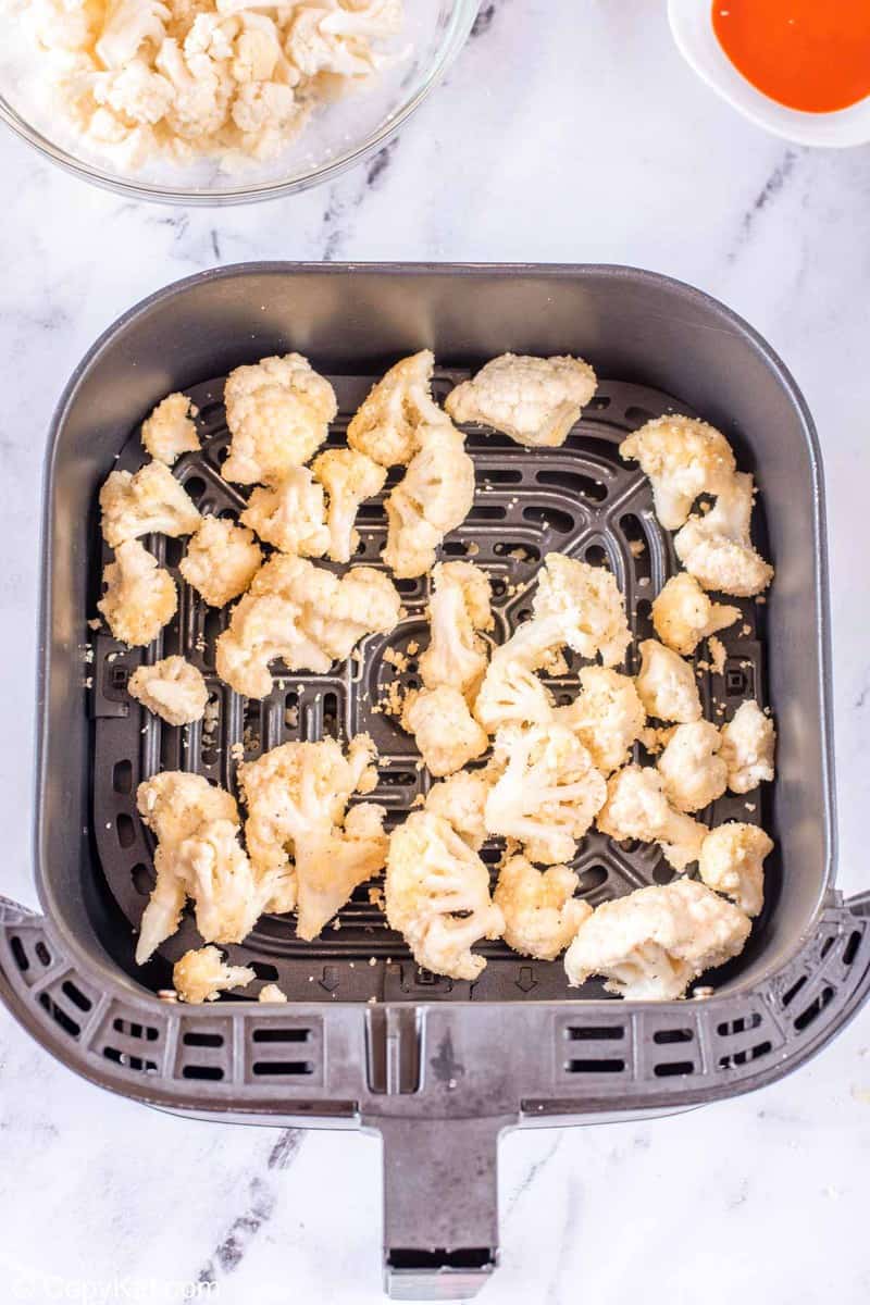 seasoned and coated cauliflower in an air fryer basked