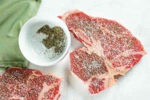 two steaks seasoned with salt and pepper