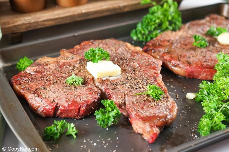 two smoked steaks on a baking sheet